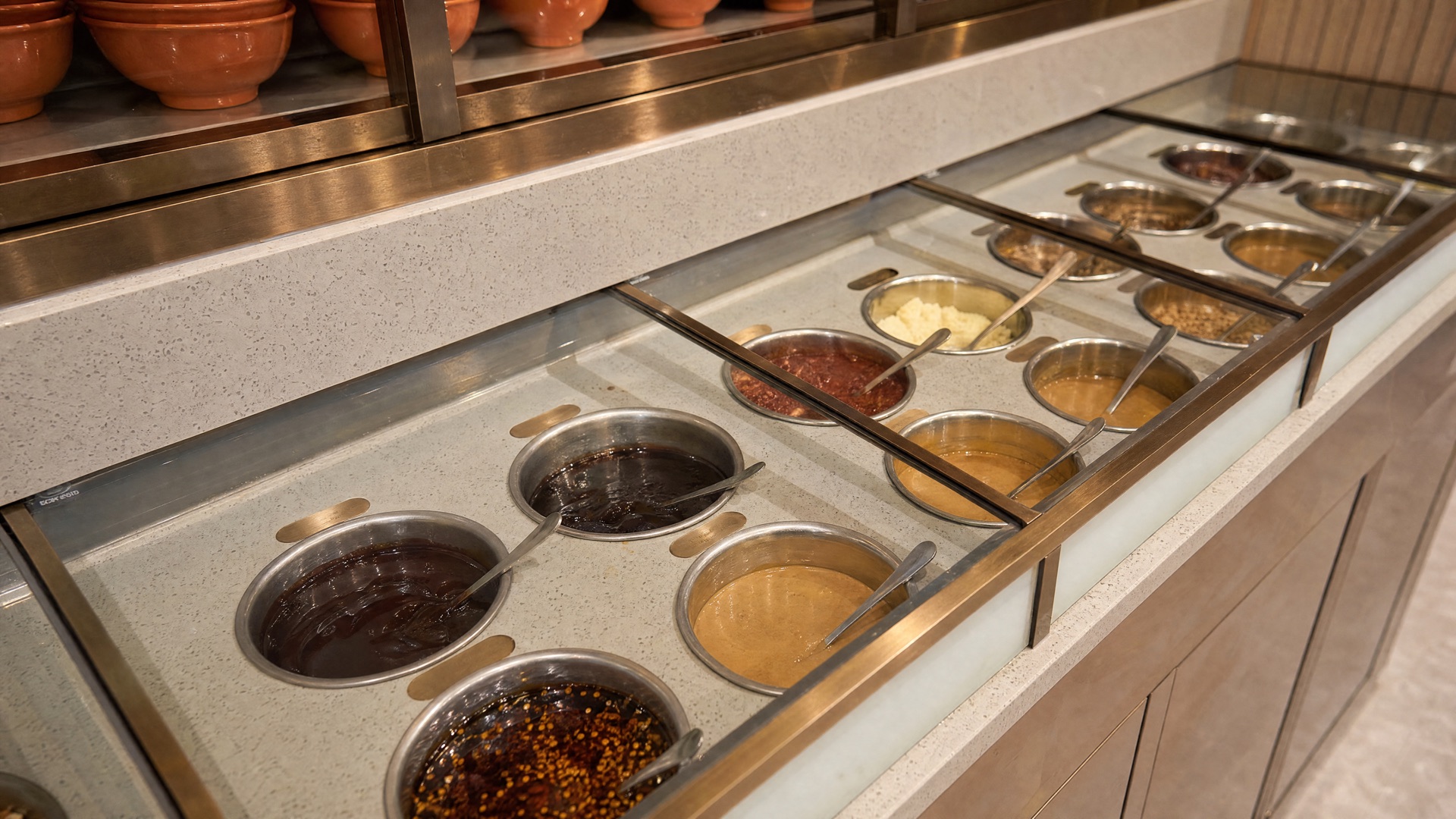 Toppings an der Theke: Erdnusssoße, Sesam, Chiliöl und Koriander